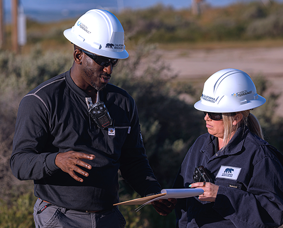 Two employees looking at a clipboard on the field